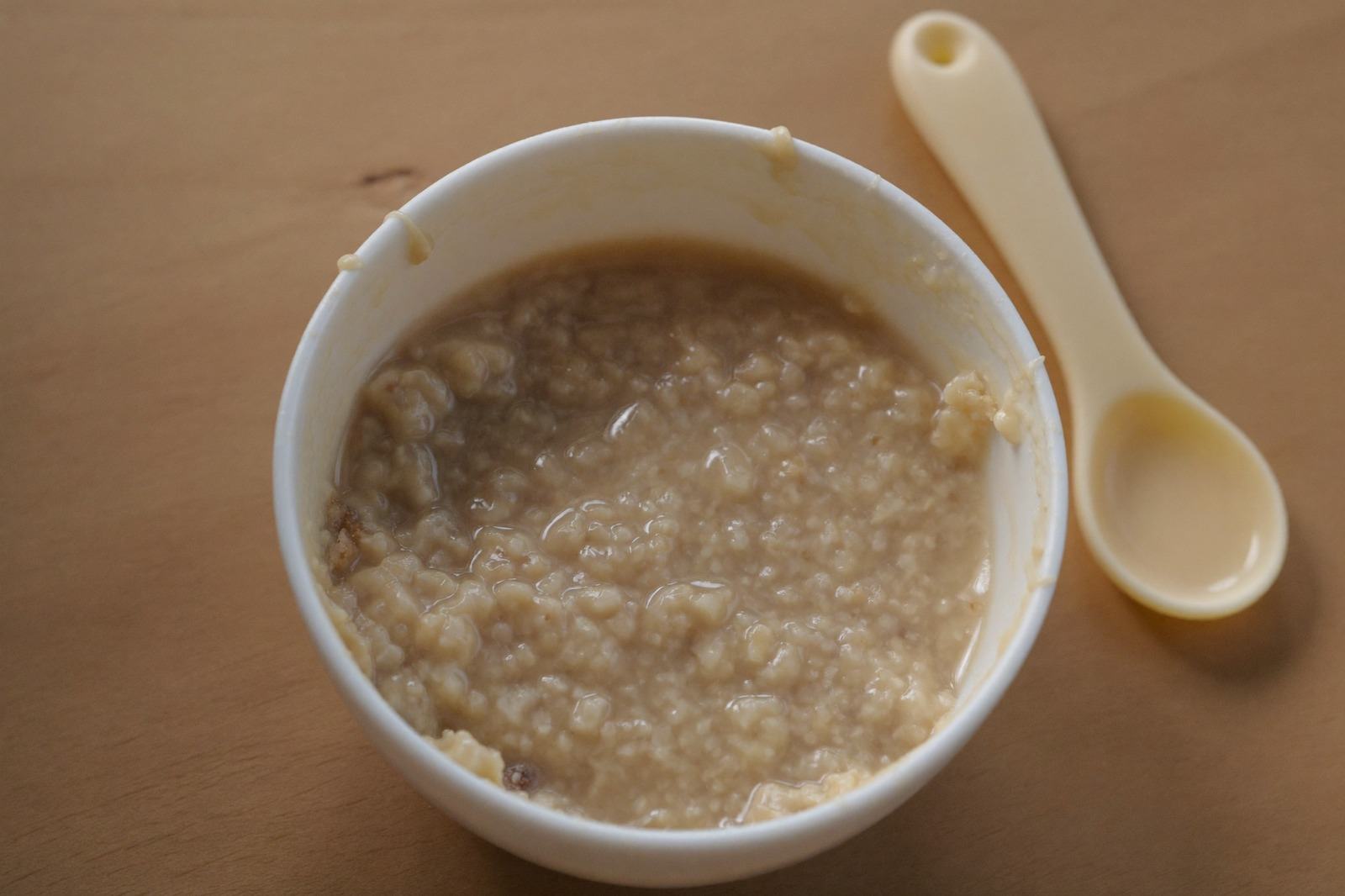 Tazón pequeño de cereal infantil recién mezclado, con una cuchara suave al lado
