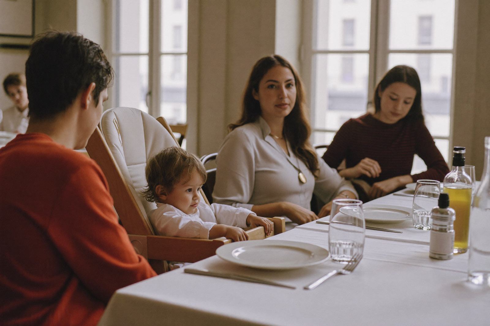 Familia sentada a la mesa de un restaurante luminoso con un niño pequeño en su silla
