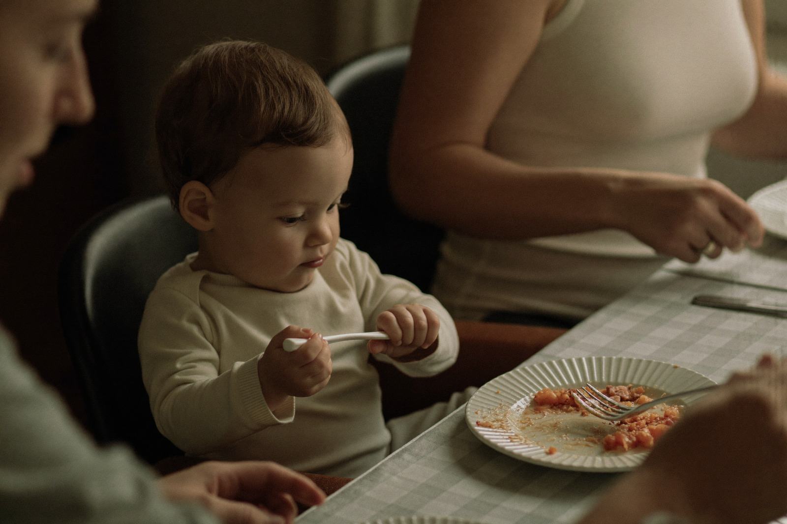 Niño pequeño sentado a la mesa mirando su plato de comida sin tocarlo
