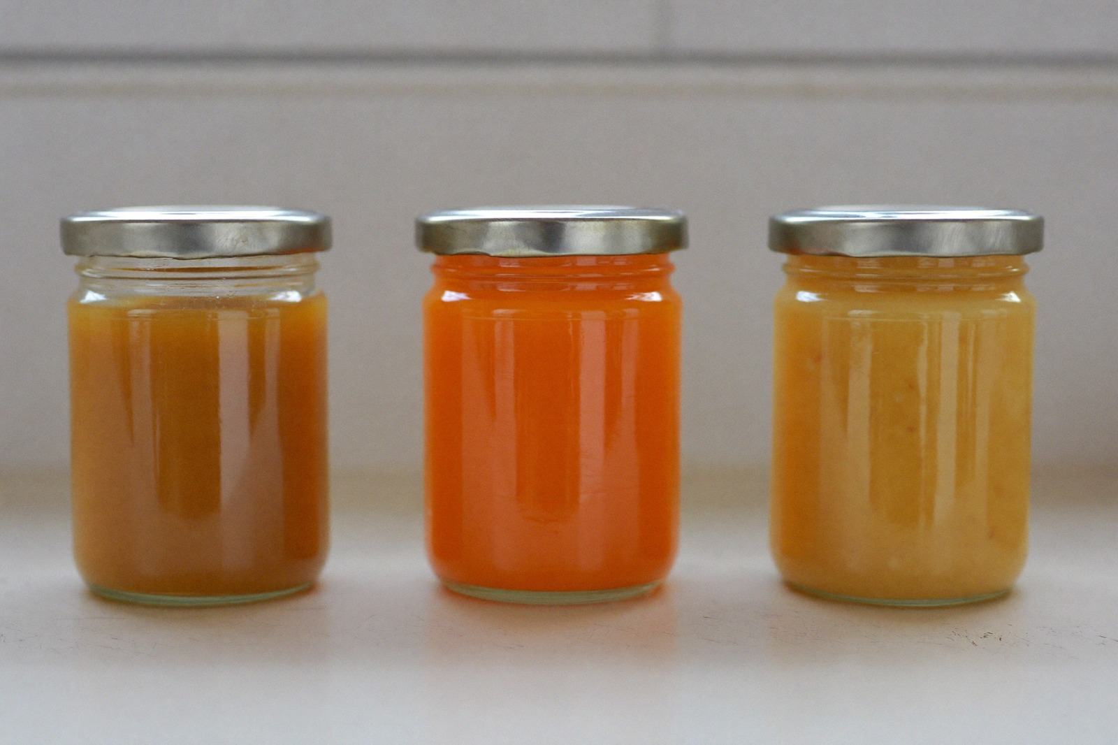 Frascos de vidrio con purés de distintos colores alineados sobre una repisa de cocina