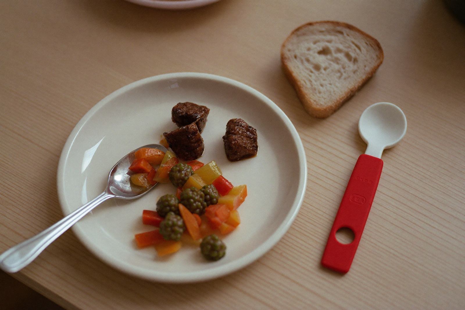 Plato de niño con verdura cocida, cubos pequeños de carne y un trozo de pan, medidos en cucharadas