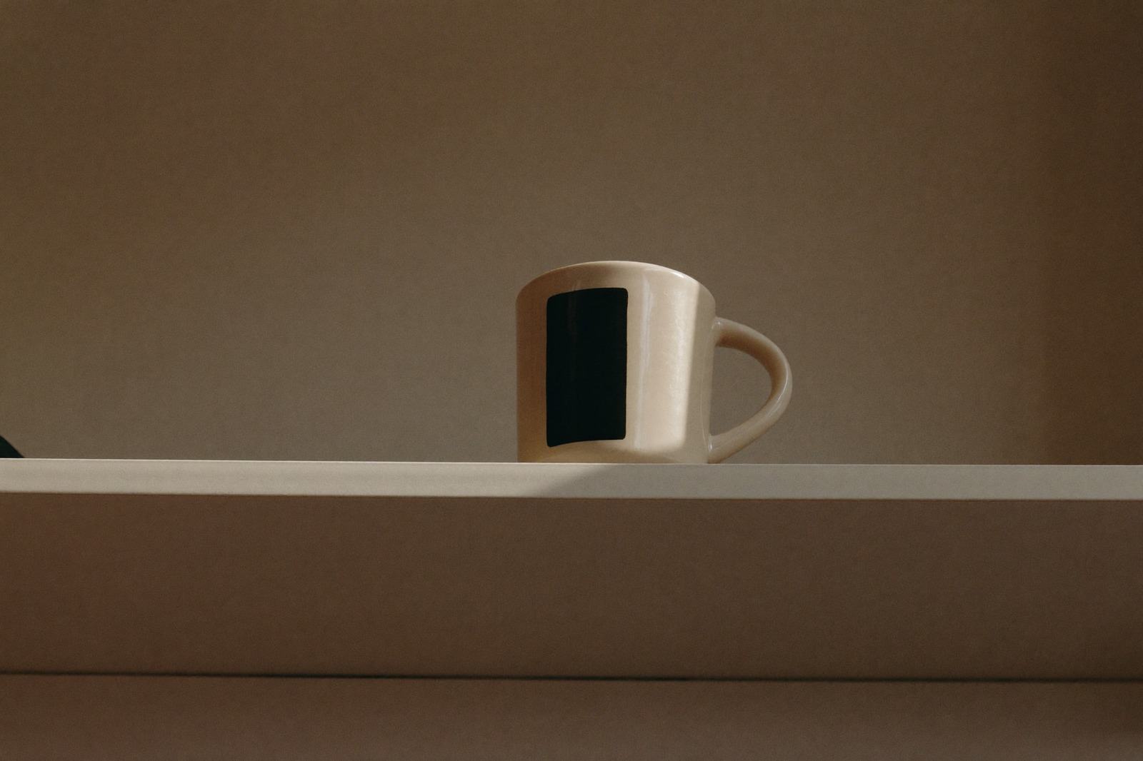 Taza de café sobre una repisa alta de cocina, fuera del alcance de la barra