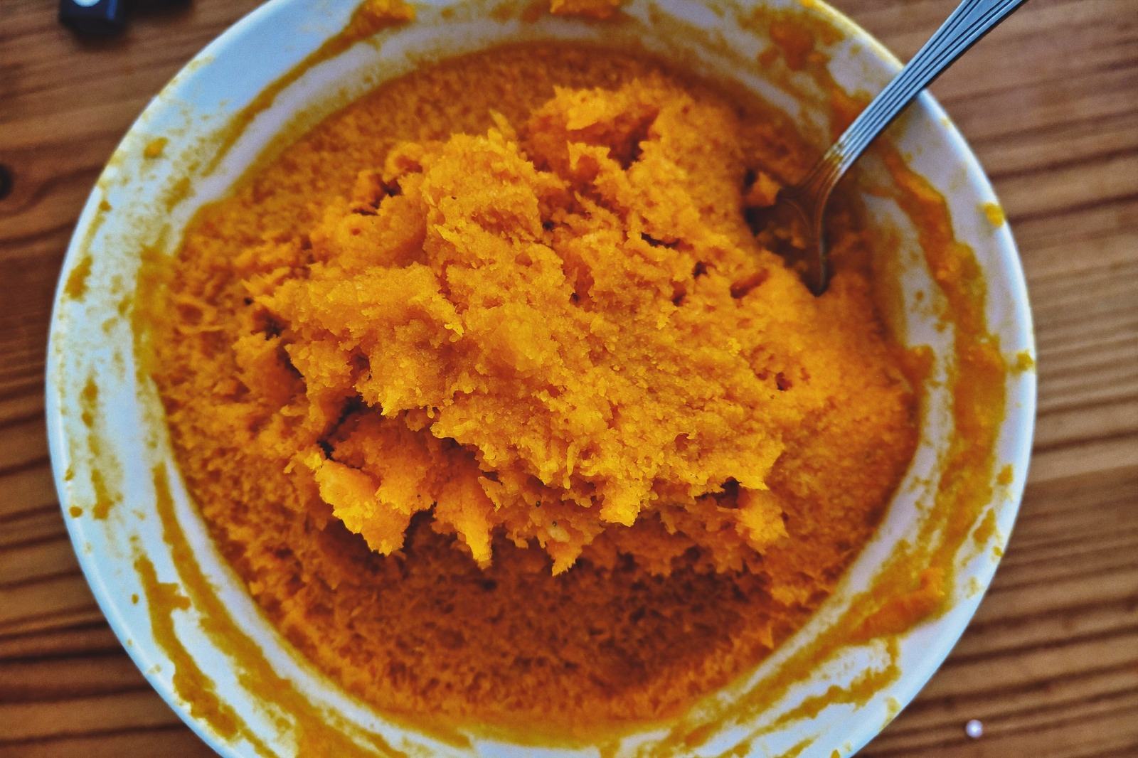 Tazón con puré machacado con grumos visibles y un tenedor apoyado en el borde