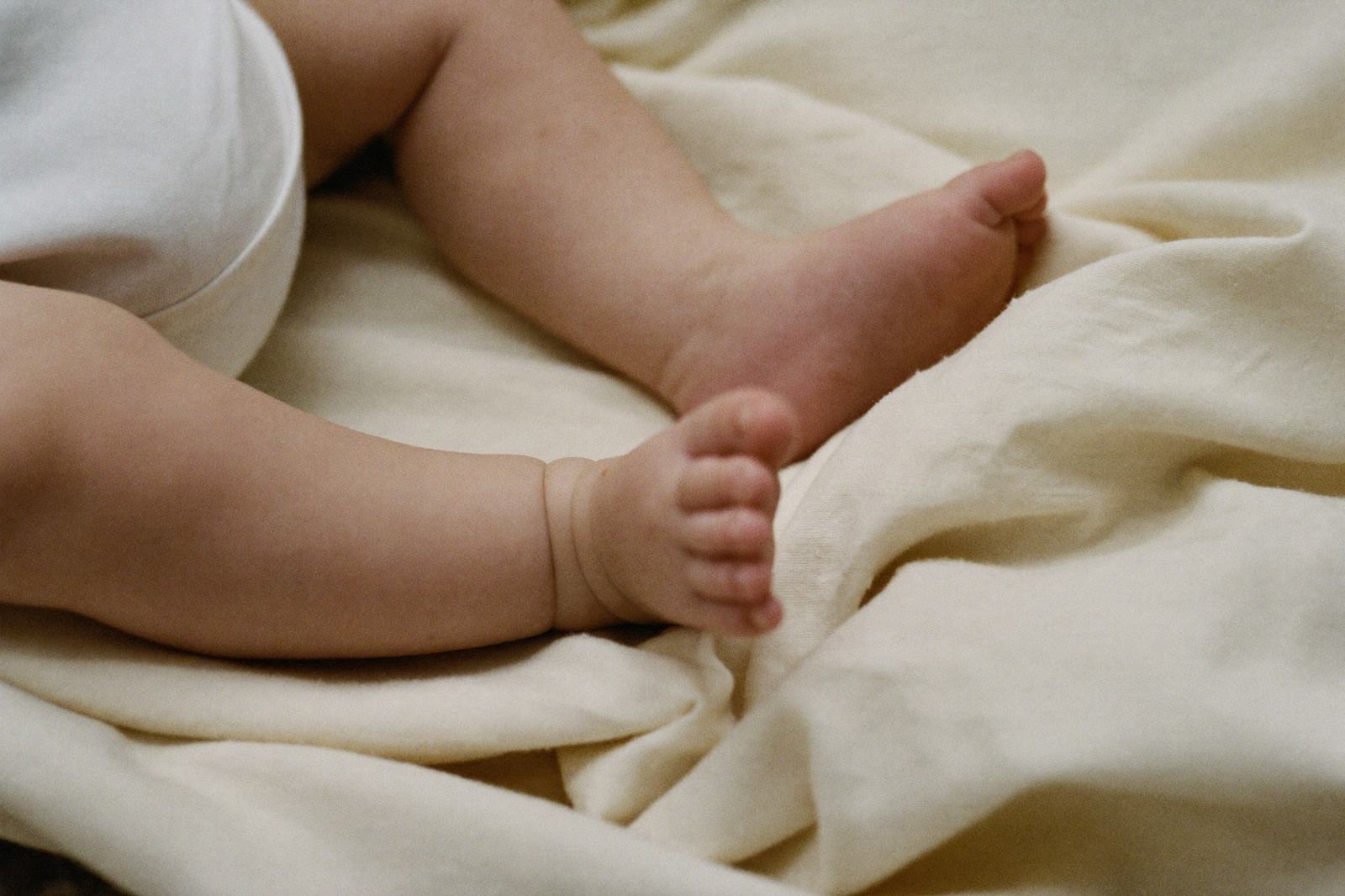 Pies descalzos de un bebé sobre una manta de algodón claro