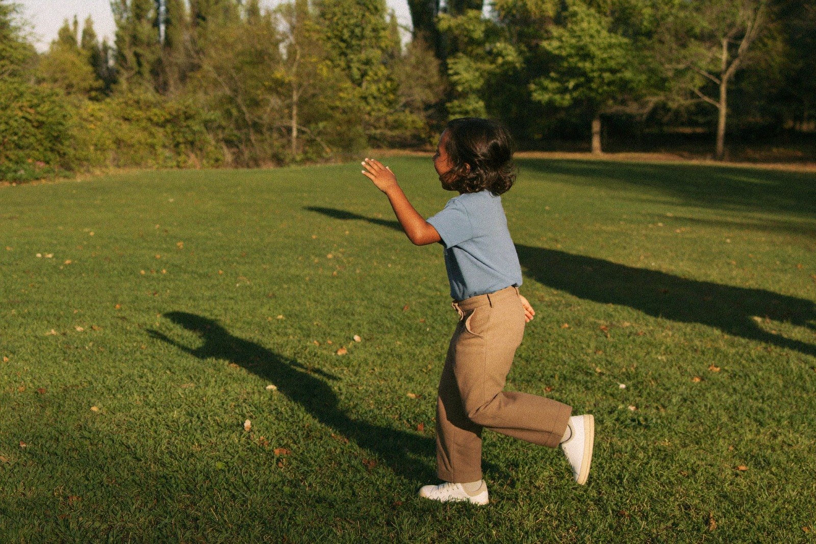 Niño en edad preescolar corriendo sobre el pasto de un parque