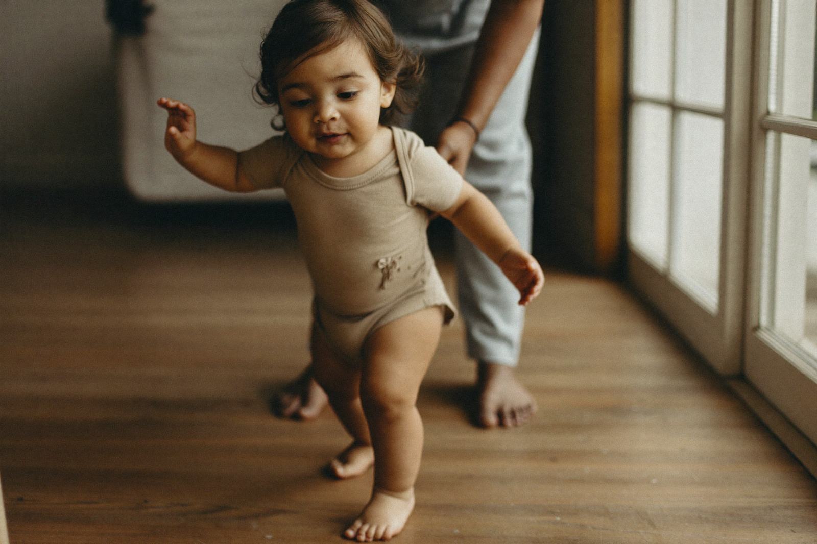Pies descalzos de un niño pequeño dando pasos sobre un piso de madera