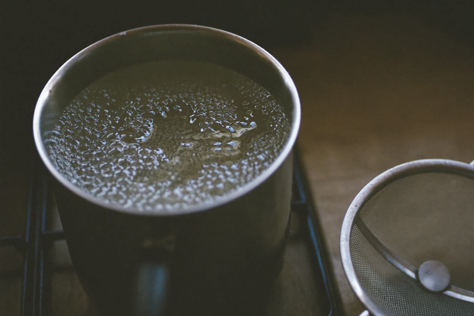 Olla pequeña con agua sobre la estufa y un colador al lado