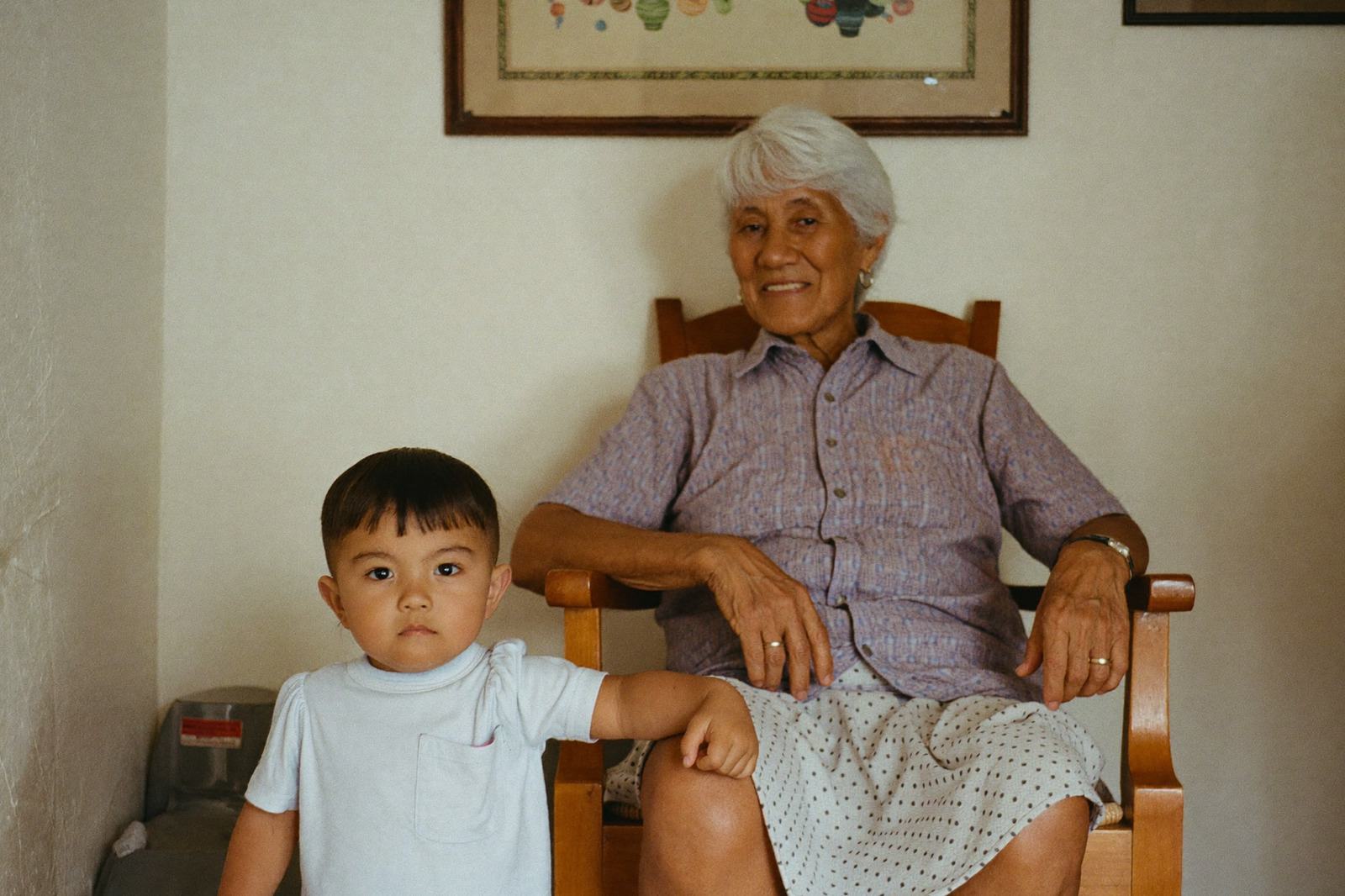 Abuela sentada en un sillón con su nieto bebé en el regazo, los dos riendo