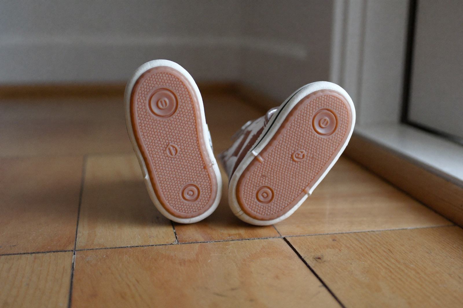 Par de zapatos pequeños de suela flexible sobre un piso de madera