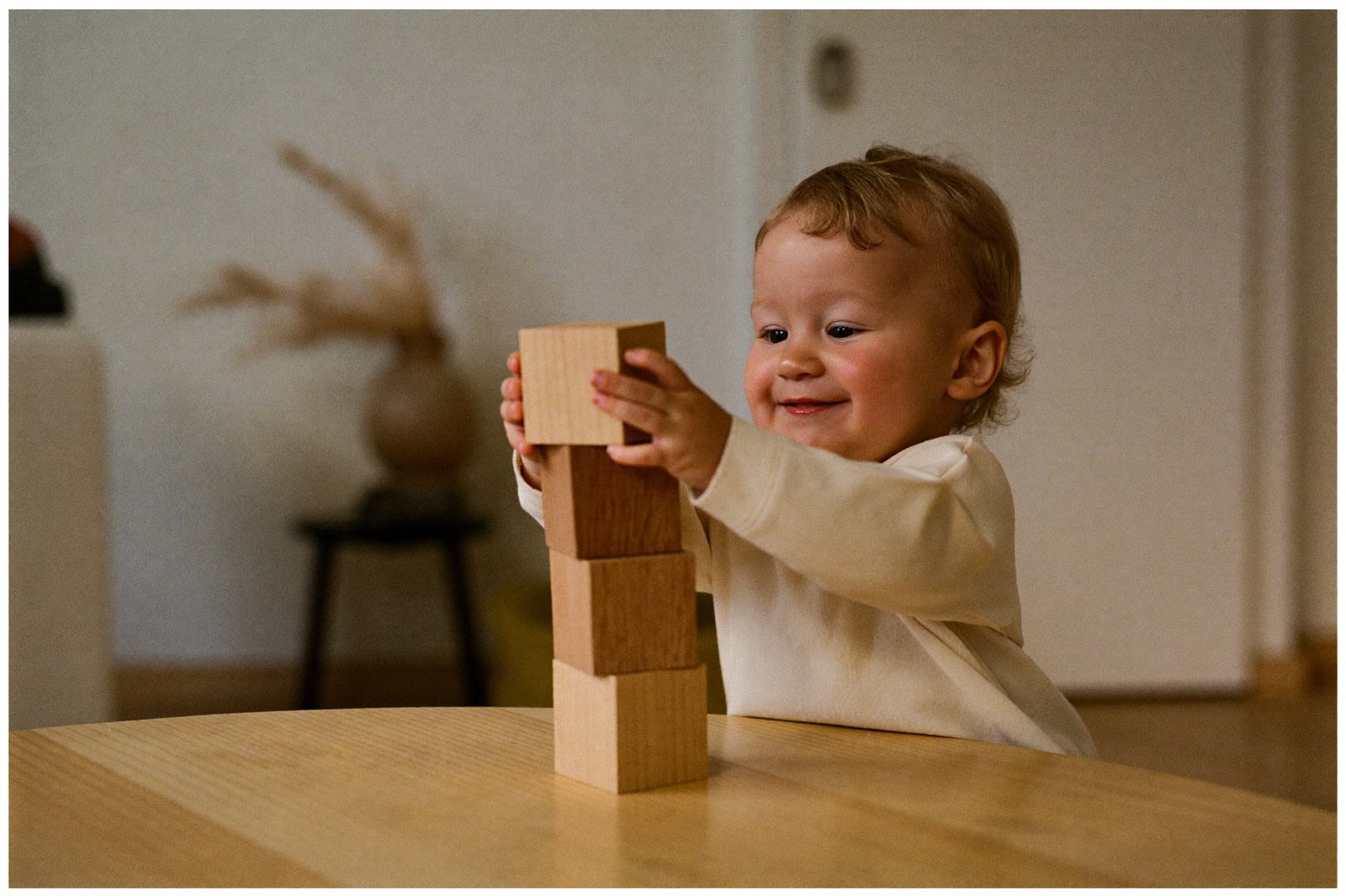 Niño pequeño sentado en el piso colocando un cubo de madera encima de otro