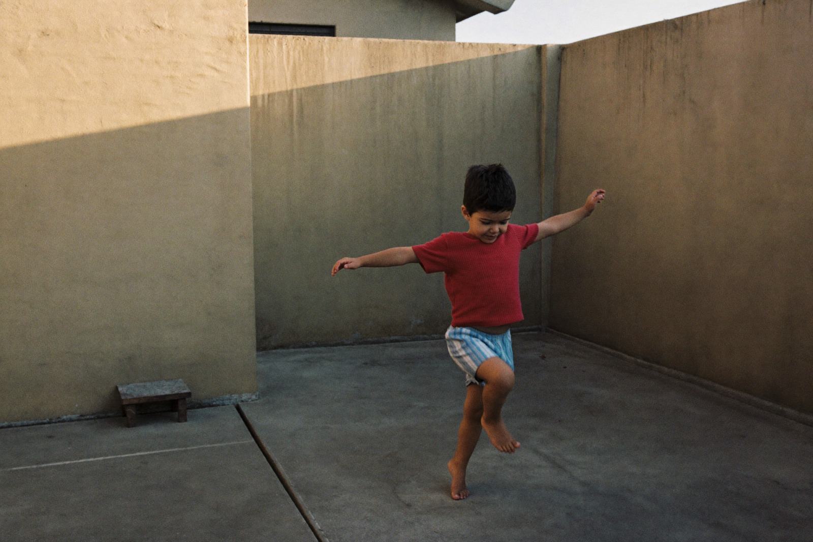 Niño pequeño saltando con los brazos extendidos en el patio de la casa