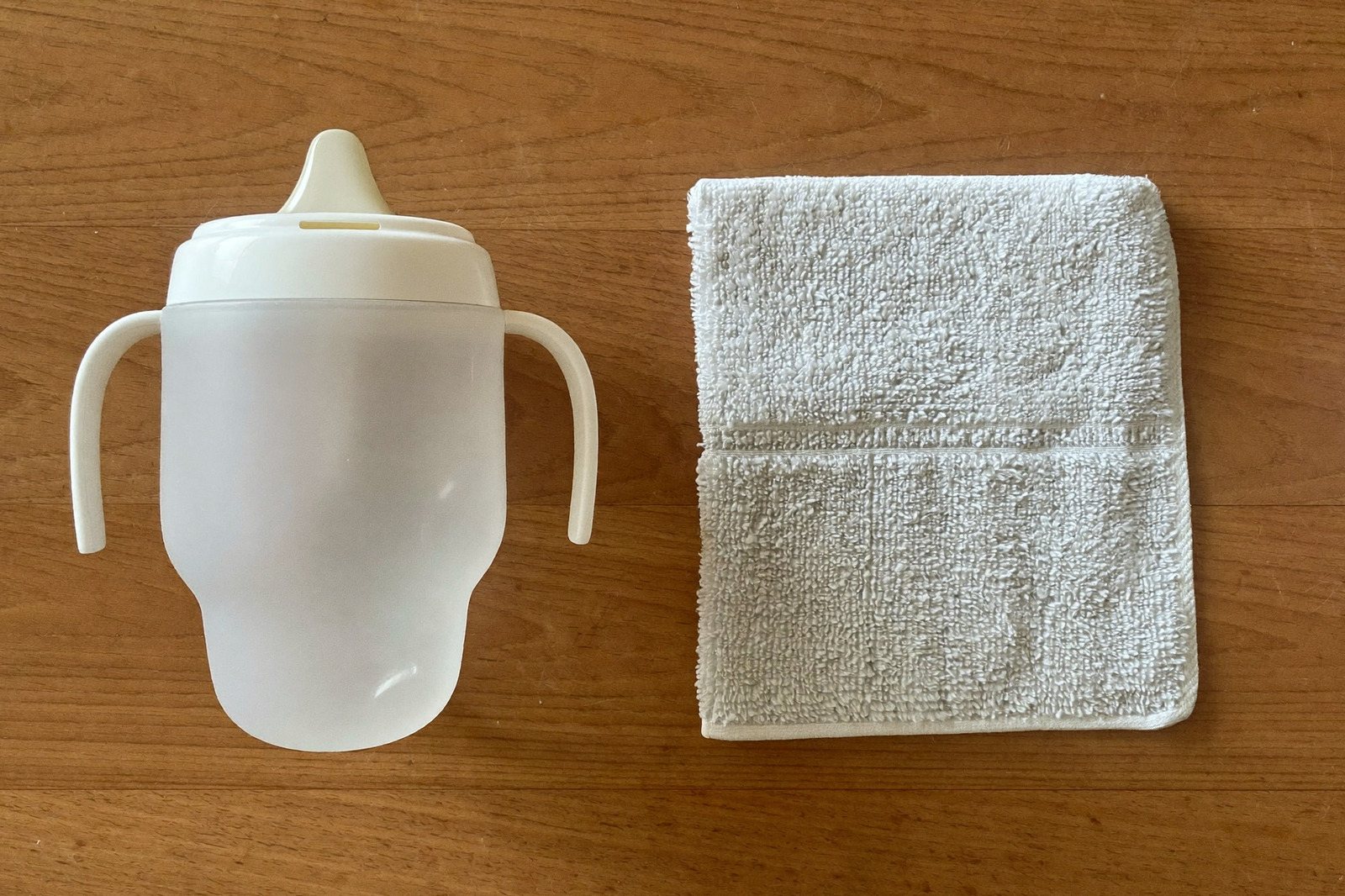 Un vaso entrenador y una toalla pequeña doblada sobre la mesa de la cocina, vistos desde arriba