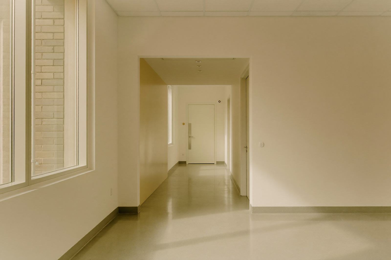 Pasillo de un hospital con la puerta de un quirófano al fondo y luz cálida