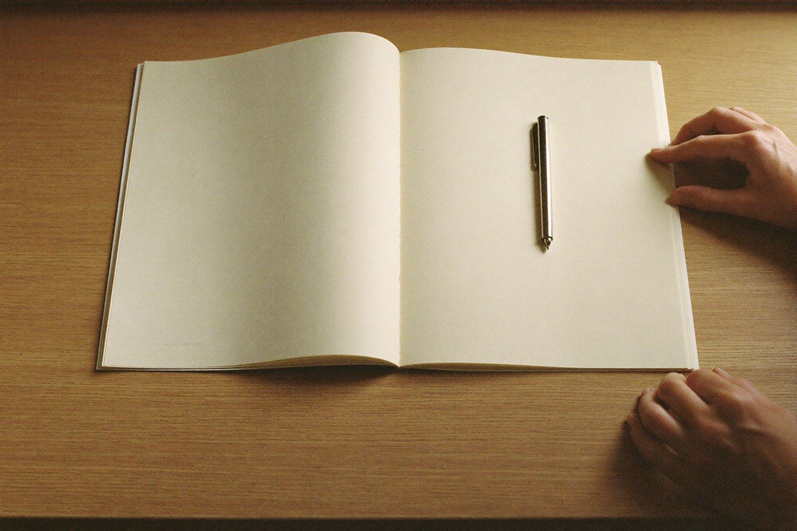 Libreta abierta y una pluma sobre la mesa de un consultorio, con las manos de una mujer apoyadas en el borde