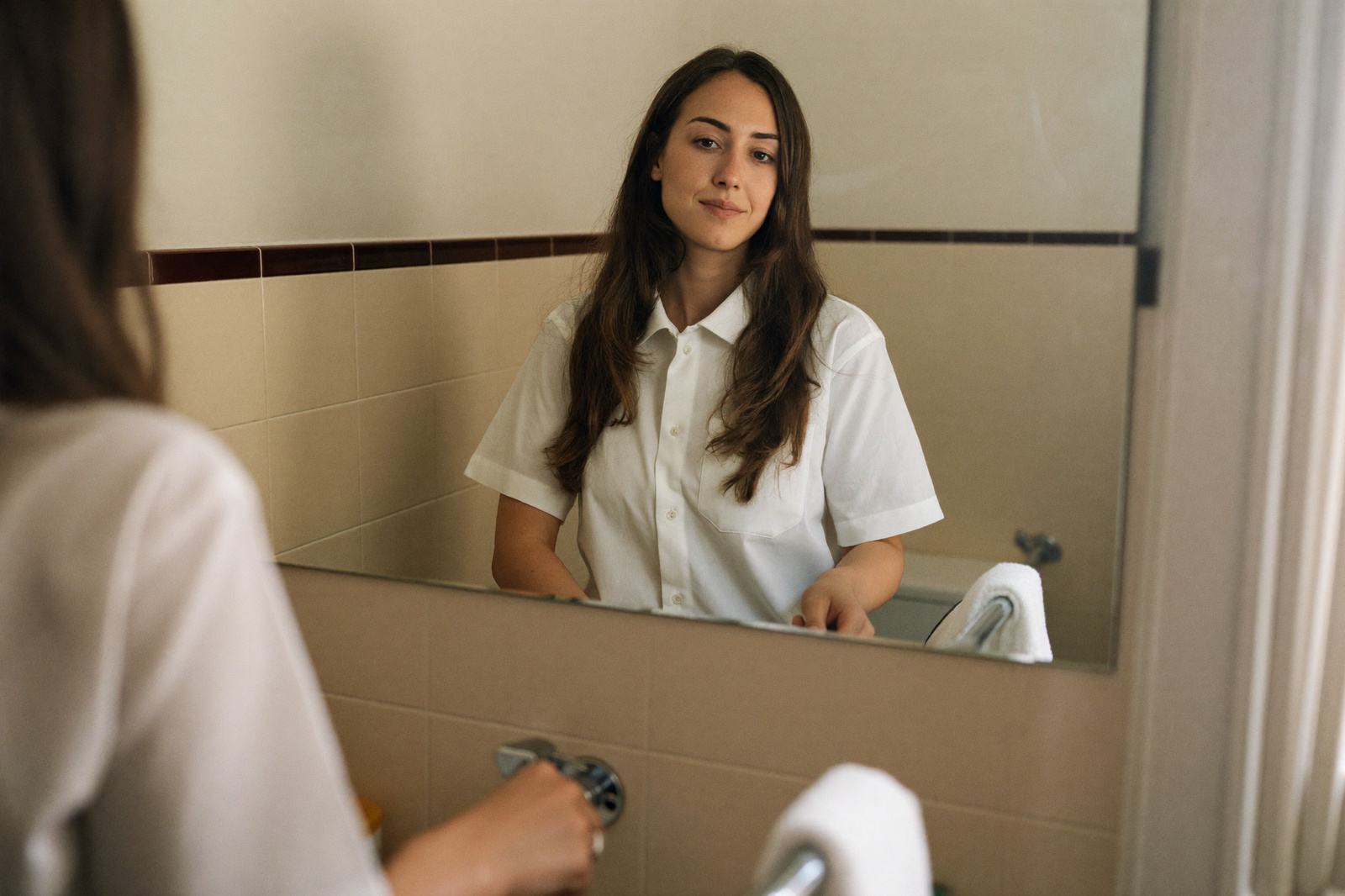 Mujer embarazada frente al espejo del baño observándose la piel del rostro con luz natural