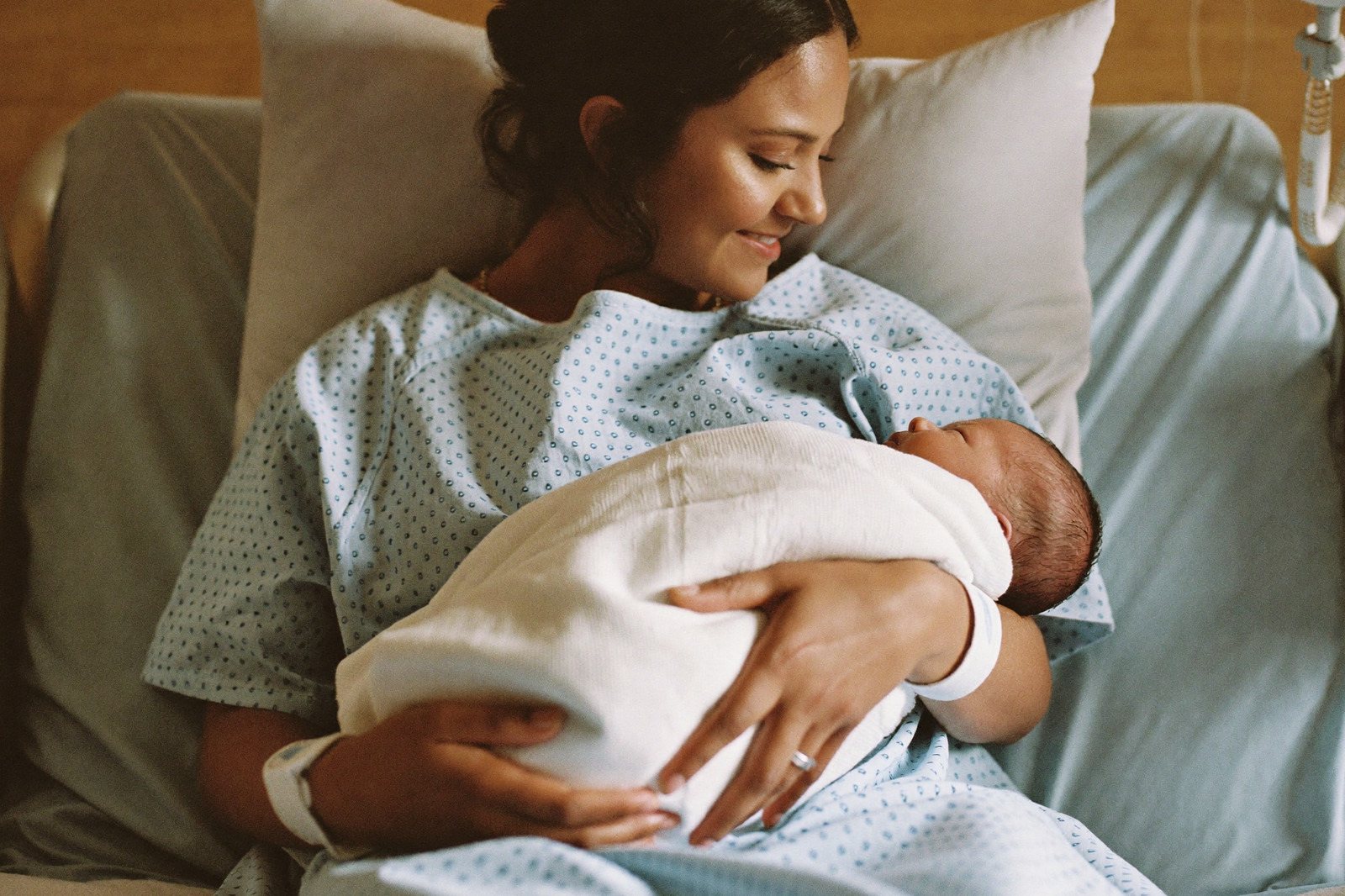 Manos de una enfermera acomodando una manta sobre un recién nacido que está sobre el pecho de su mamá