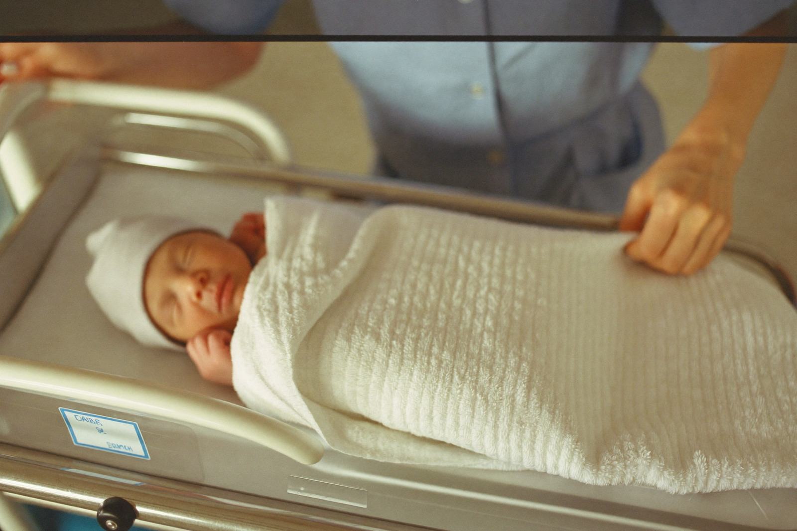 Recién nacido envuelto en una manta blanca sobre el pecho de su mamá, con luz suave