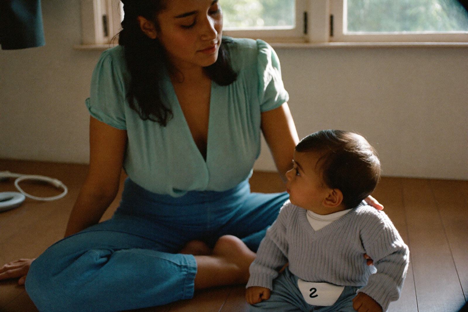 Una madre sentada frente a su bebé de nueve meses, hablándole de cerca mientras el bebé la mira a la boca