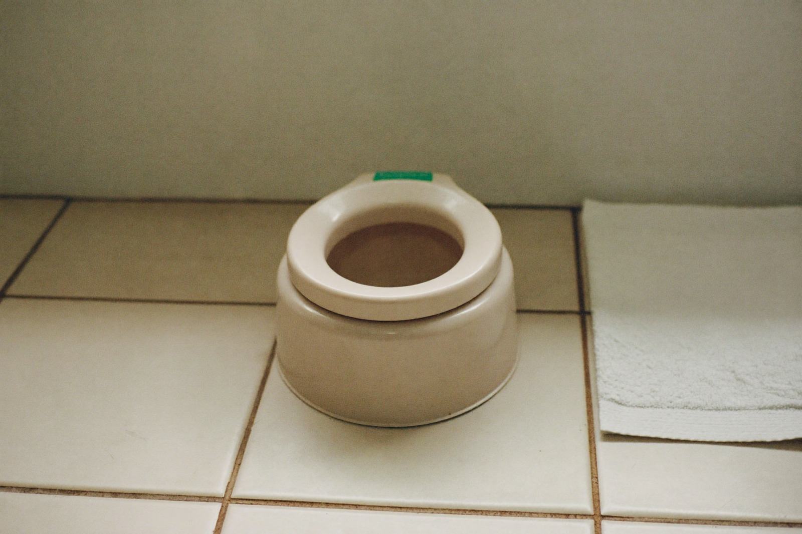 Bacinica infantil de plástico claro en el piso de un baño con luz natural