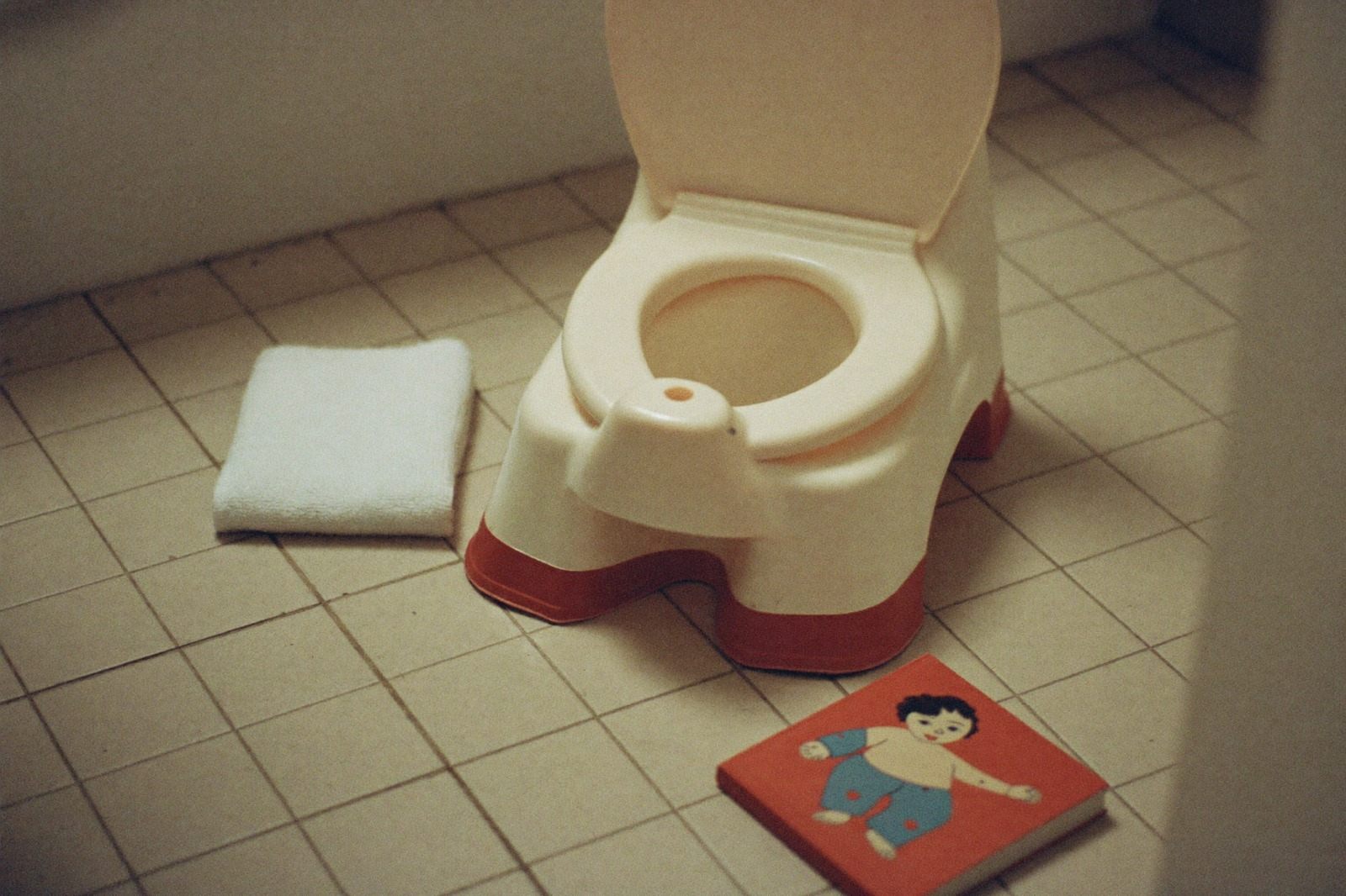 Bacinica infantil de plástico en el piso de un baño con luz suave