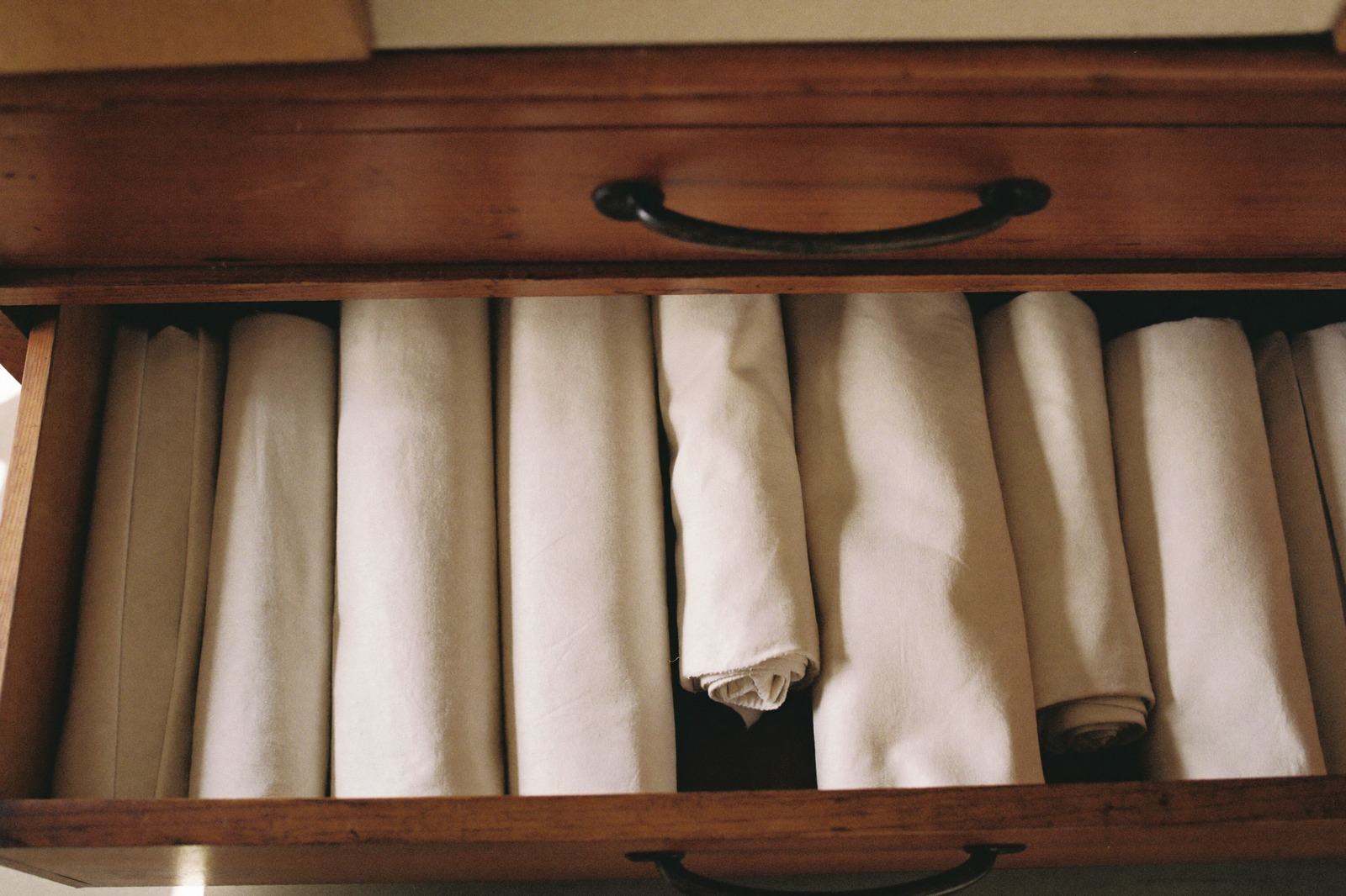 Cajón de madera abierto con pañales de tela enrollados y acomodados en filas