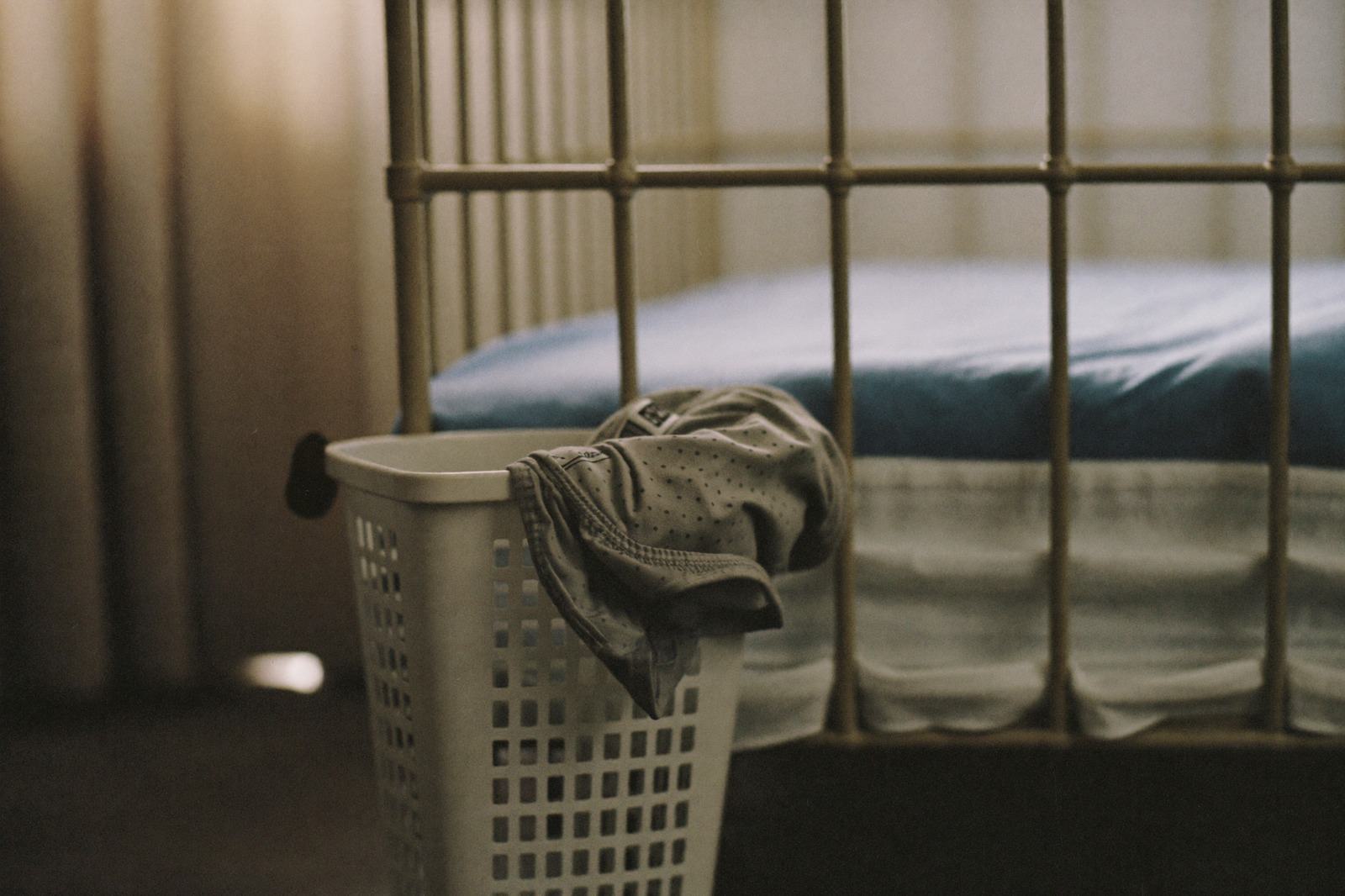 Cesto de ropa con prendas dobladas junto a la cama de un niño pequeño