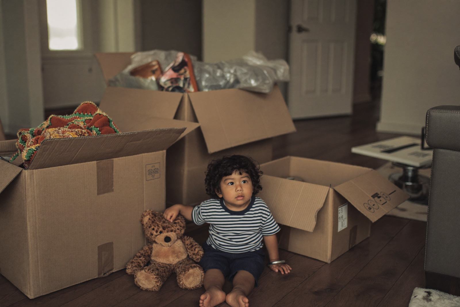 Cajas de mudanza apiladas en una habitación con una mochila infantil encima
