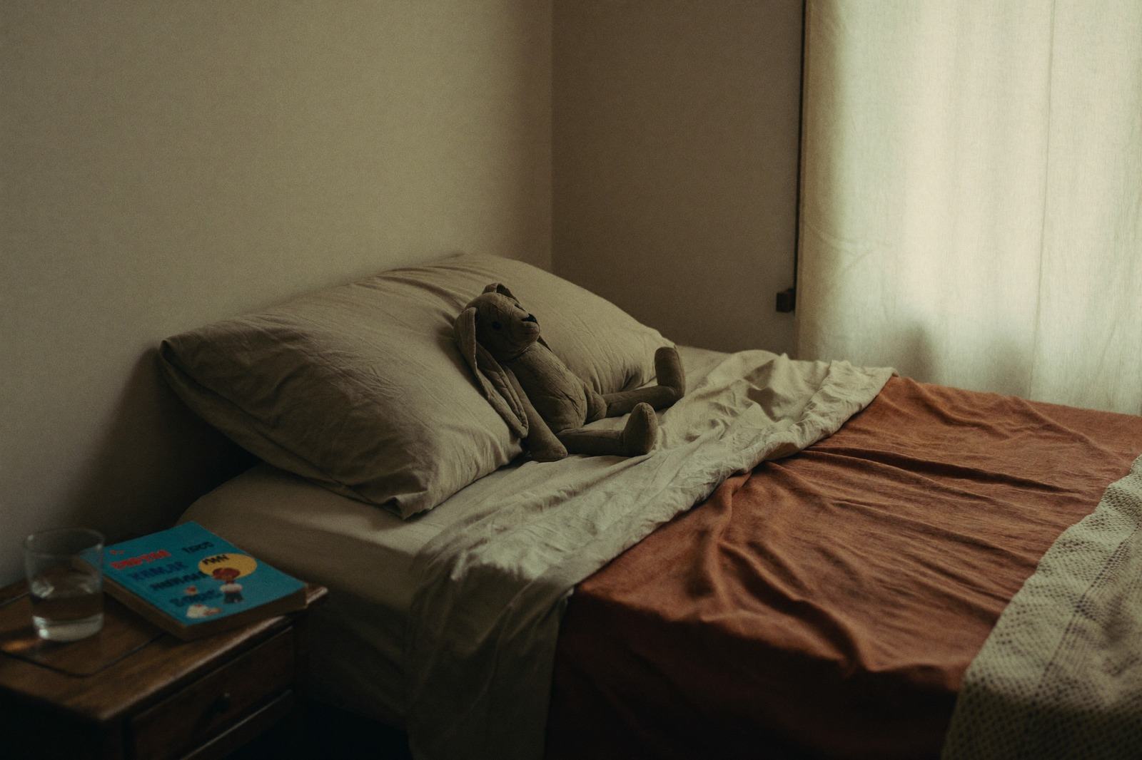 Cama infantil con la luz baja de la noche y un libro en el buró