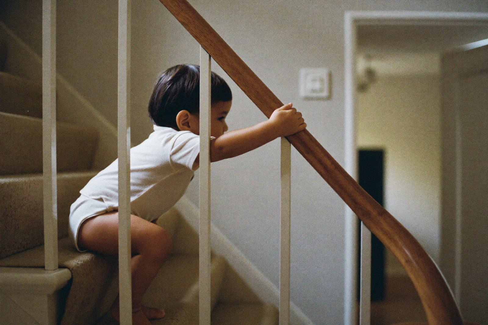 Niño pequeño subiendo con cuidado un escalón sujetándose del barandal