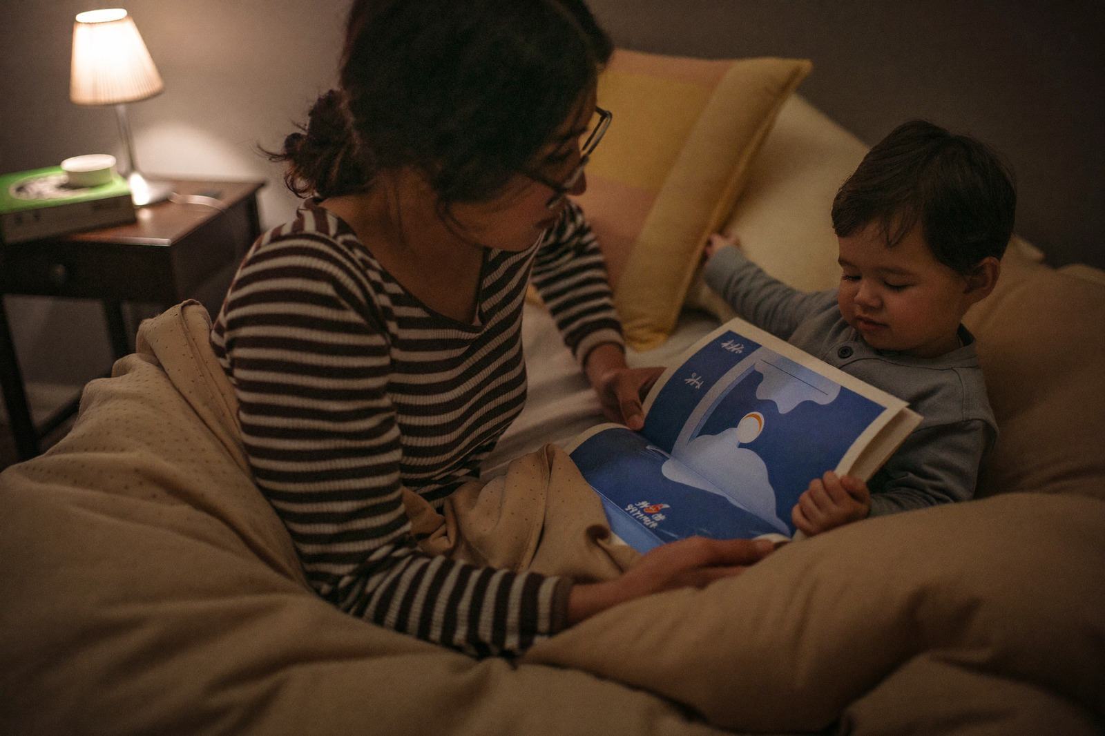 Habitación infantil en penumbra con una lámpara encendida y un libro sobre la cama