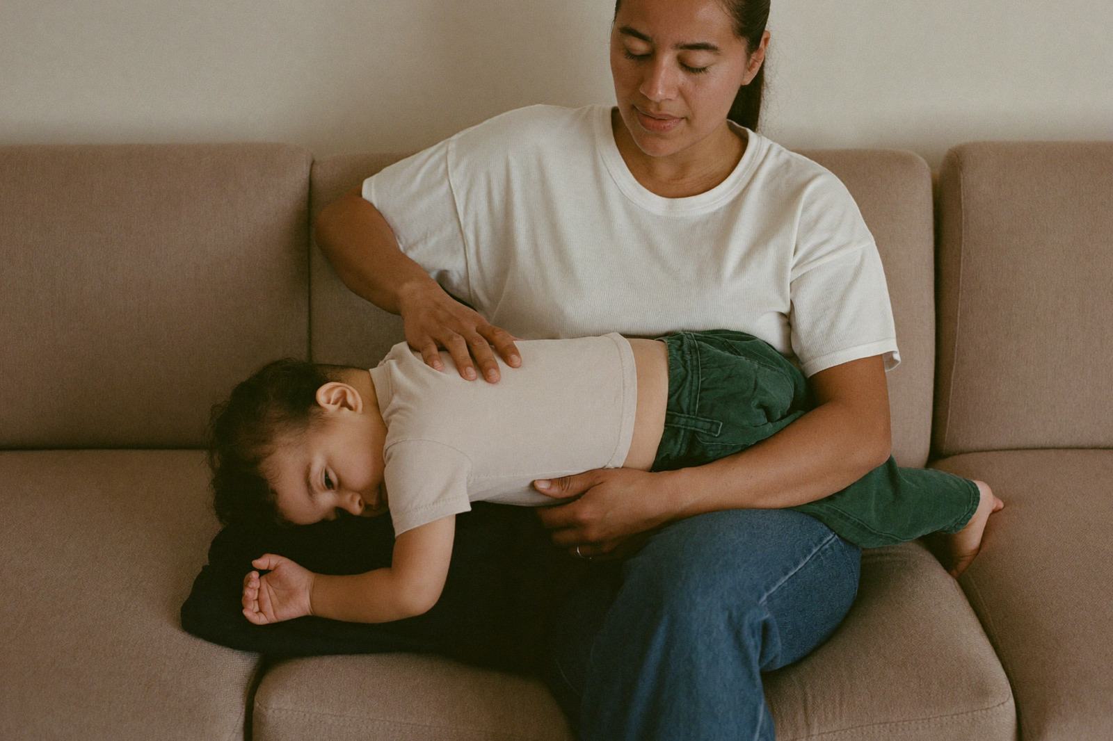 Niño pequeño recostado en el sillón mientras su mamá le escucha la respiración