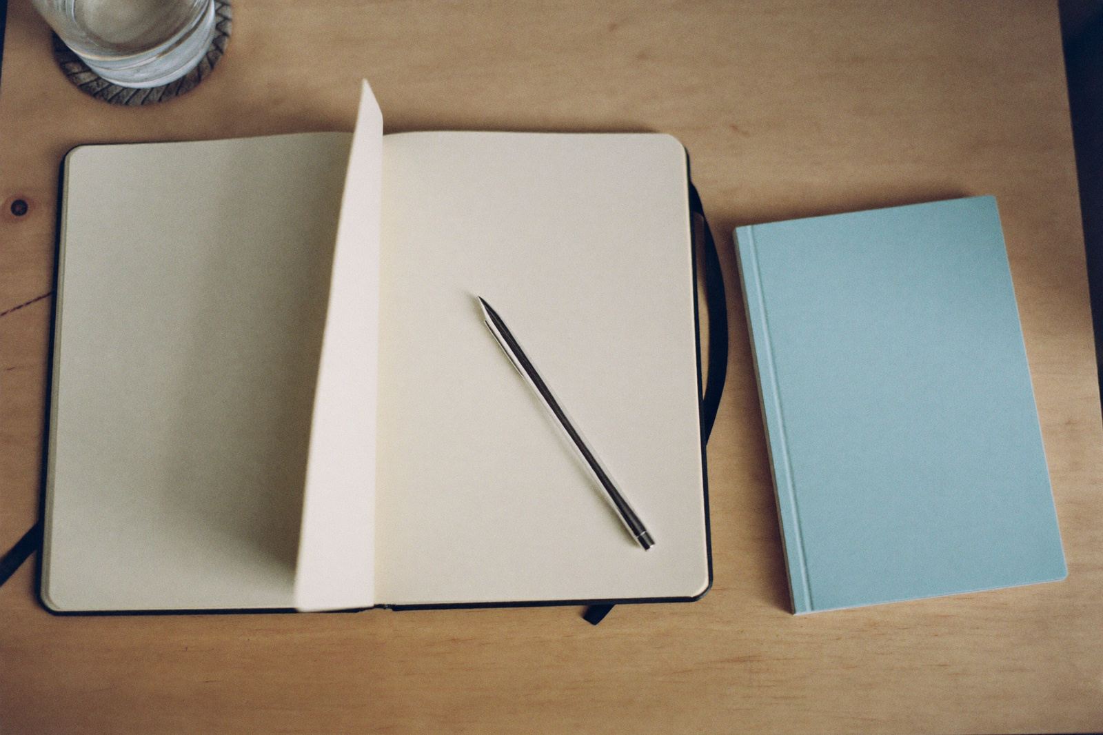 Libreta abierta con una pluma encima, junto a un cuadernillo de salud cerrado, sobre un escritorio de madera clara