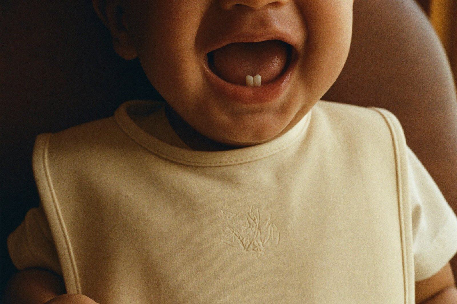 Primer plano de la boca abierta de un bebé sonriendo, con los dos dientes inferiores frontales recién salidos entre las encías