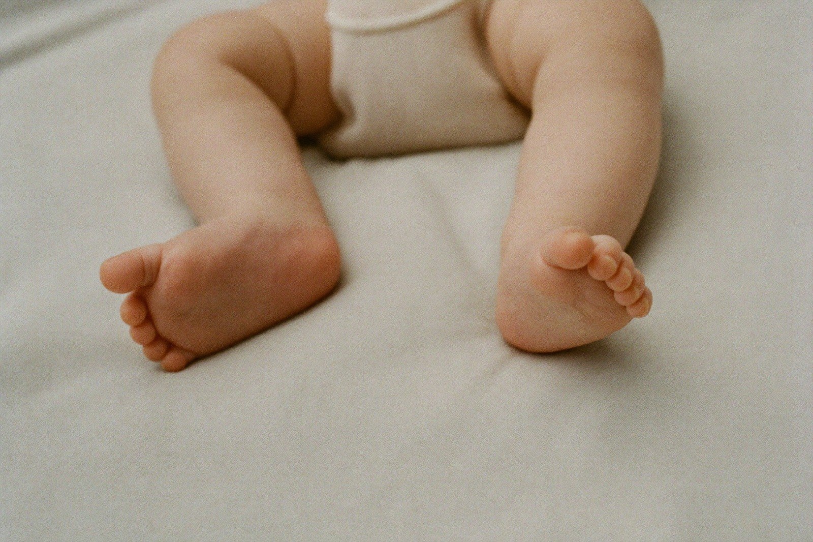 Primer plano de los pies de un bebé sobre una manta de algodón claro