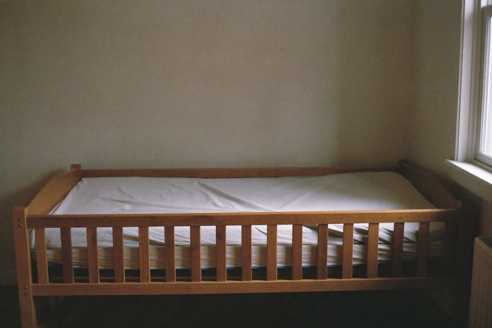 Cuna con colchón firme y sábana ajustada, completamente vacía, sin almohadas ni peluches