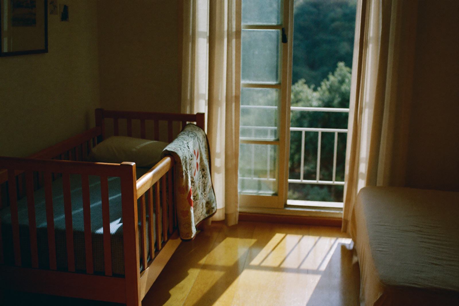 Cuna de madera junto a una ventana abierta, con la luz de la mañana entrando al cuarto