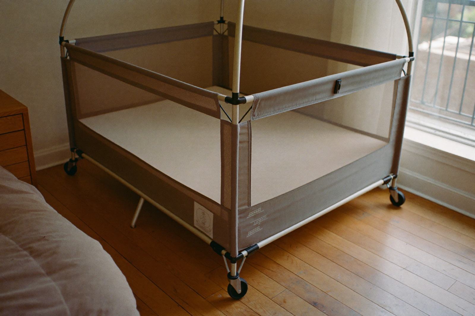 Corral de viaje armado en una habitación, con la base plana cubierta por una sábana ajustada