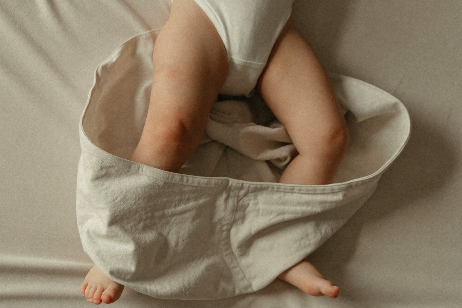 Bebé envuelto con la tela holgada a la altura de las piernas, con espacio visible para mover las caderas