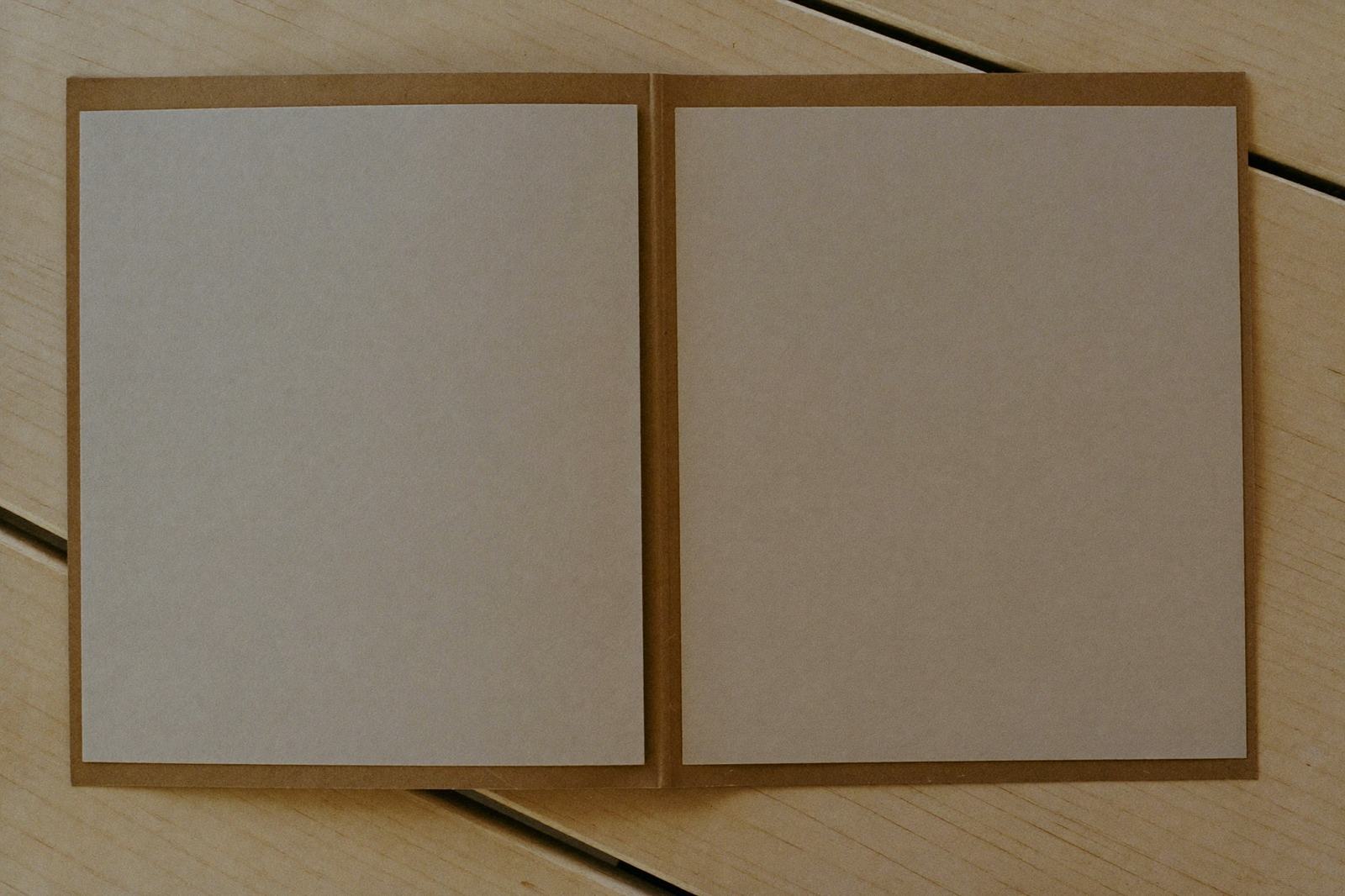 Carpeta de cartón lisa y sin marcas con hojas dentro, sobre una mesa de madera clara