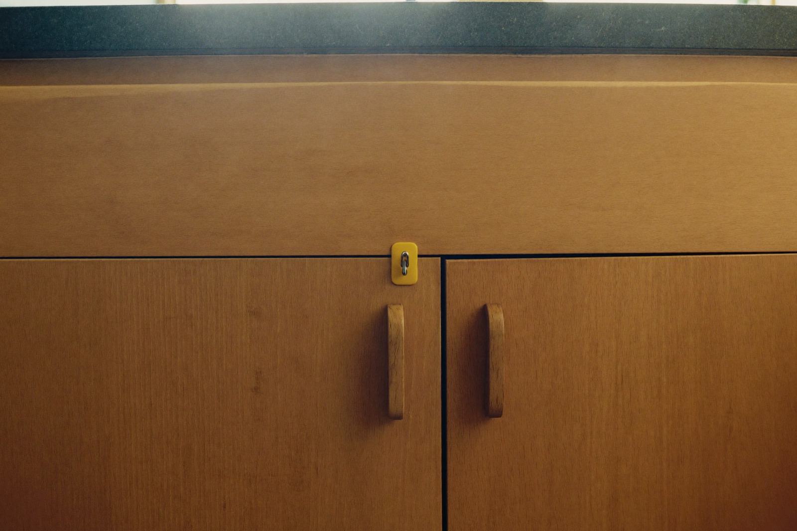 Gabinete bajo el fregadero de una cocina, con puerta cerrada y un pestillo de seguridad instalado