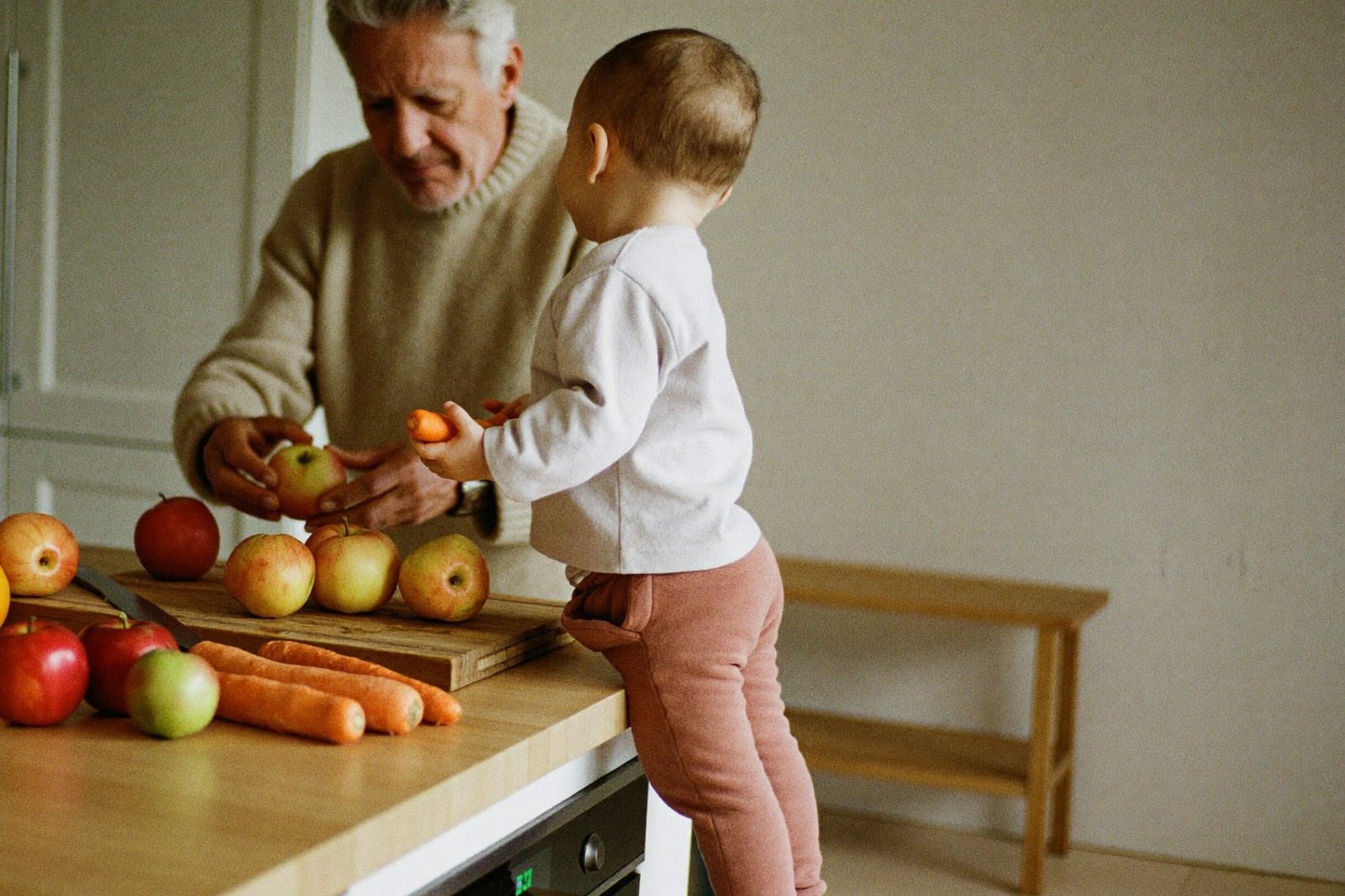 Persona mayor y un niño pequeño preparando comida juntos en la cocina