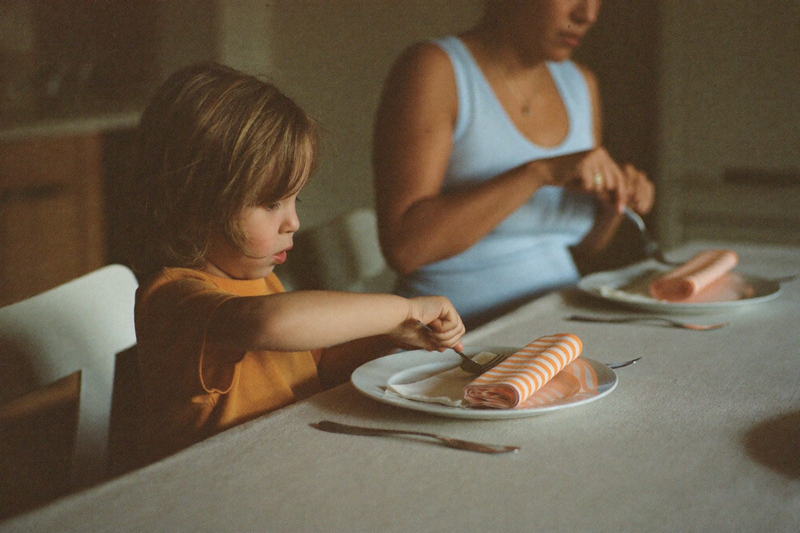 Niño pequeño sirviéndose en la mesa junto a su mamá a la hora de la comida