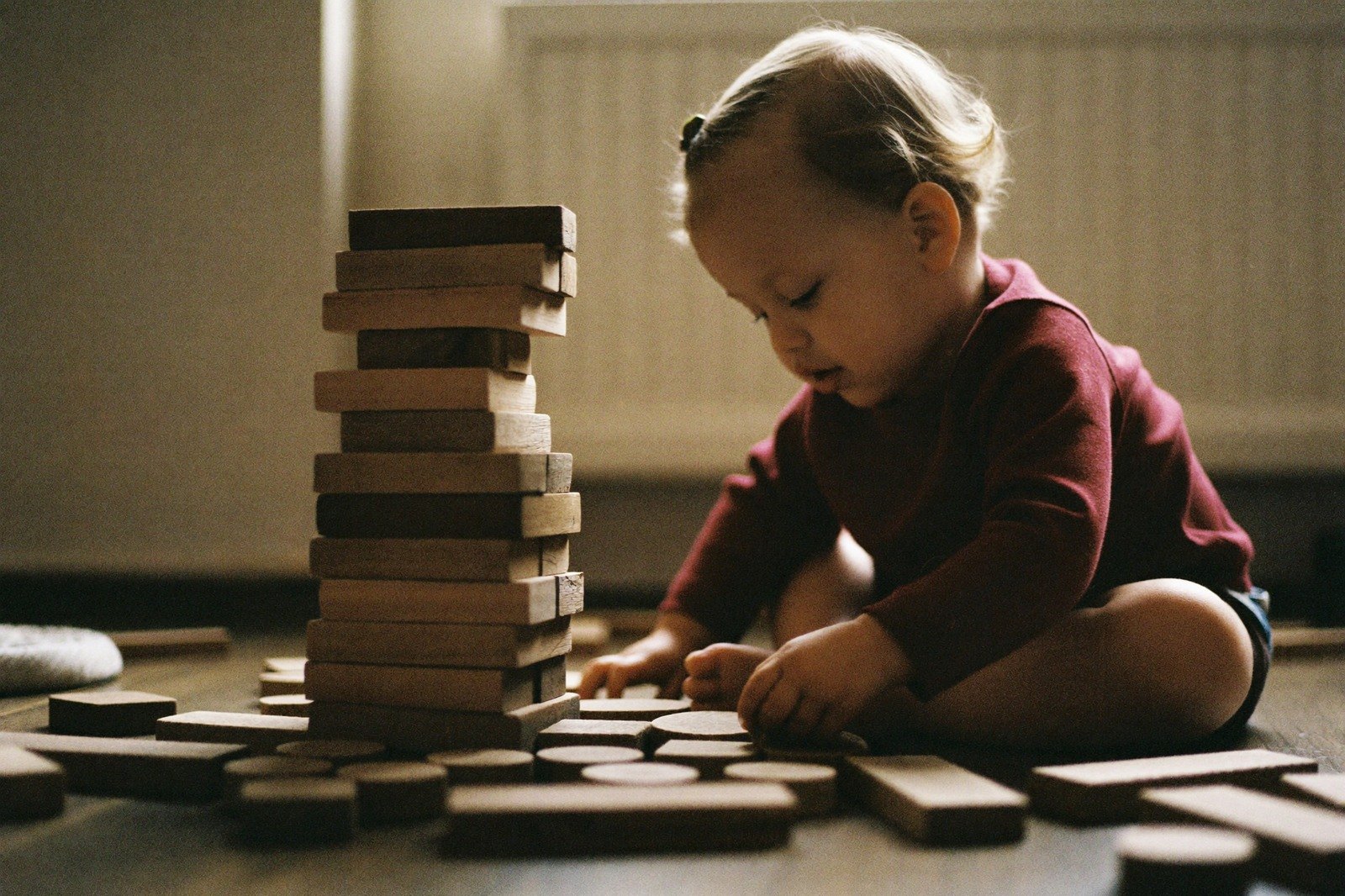 Niño pequeño jugando con bloques de madera en el piso de la sala