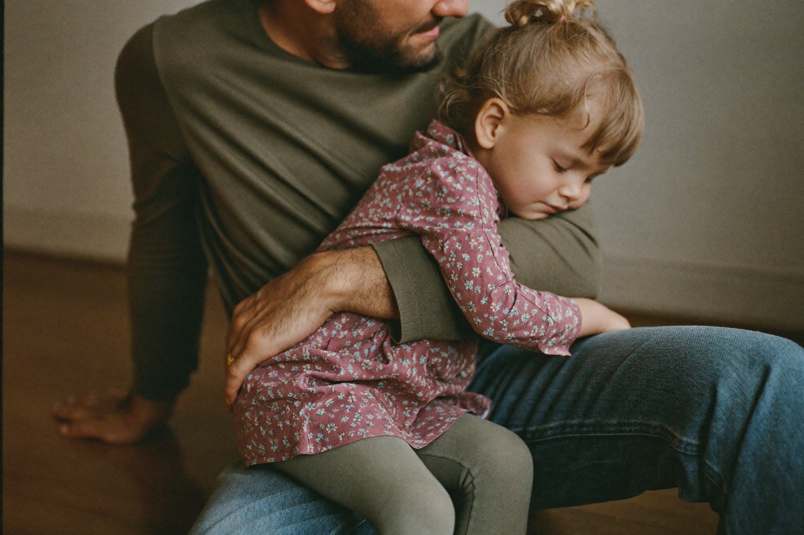 Papá abrazando a su hija de tres años sentados en el sillón
