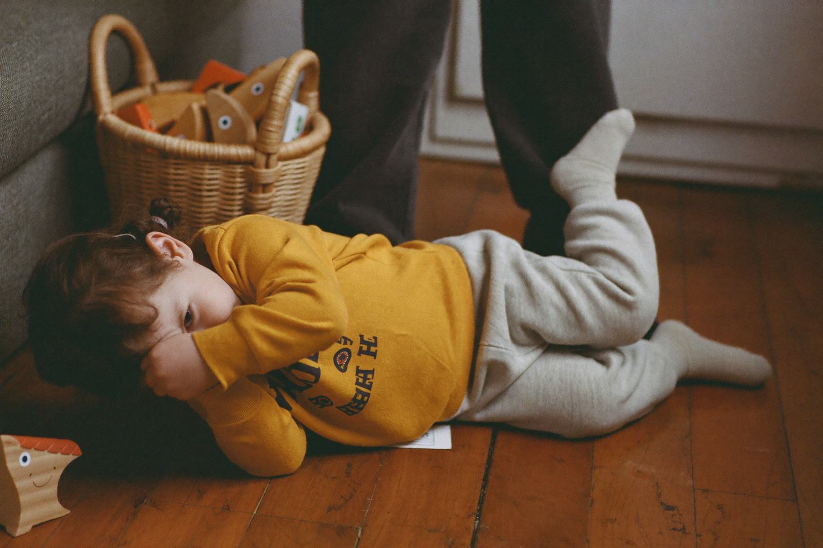 Niña de tres años tirada en el piso de madera de la sala
